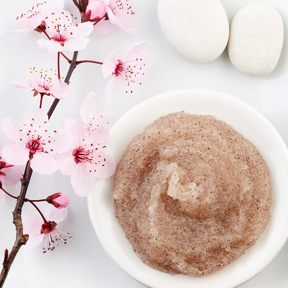 A small white dish on a white platter holds DIY Floral Sugar Scrub