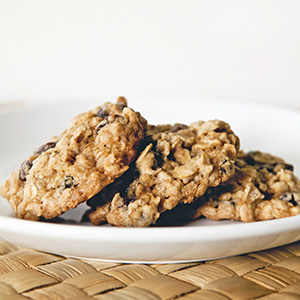 A white ceramic bowl on a wicker placemat holds Ultimate Organic Oatmeal and Goldenberry Cookies