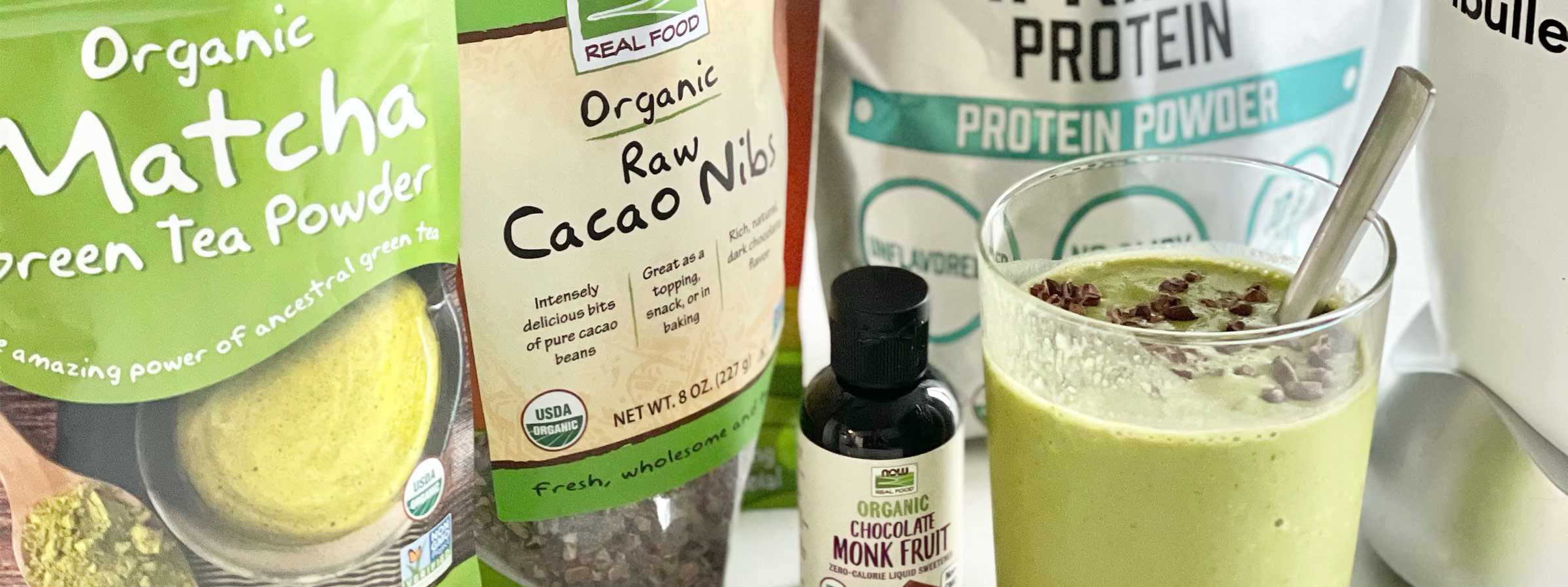 light green smoothie in a glass surrounded by ingredients to make it