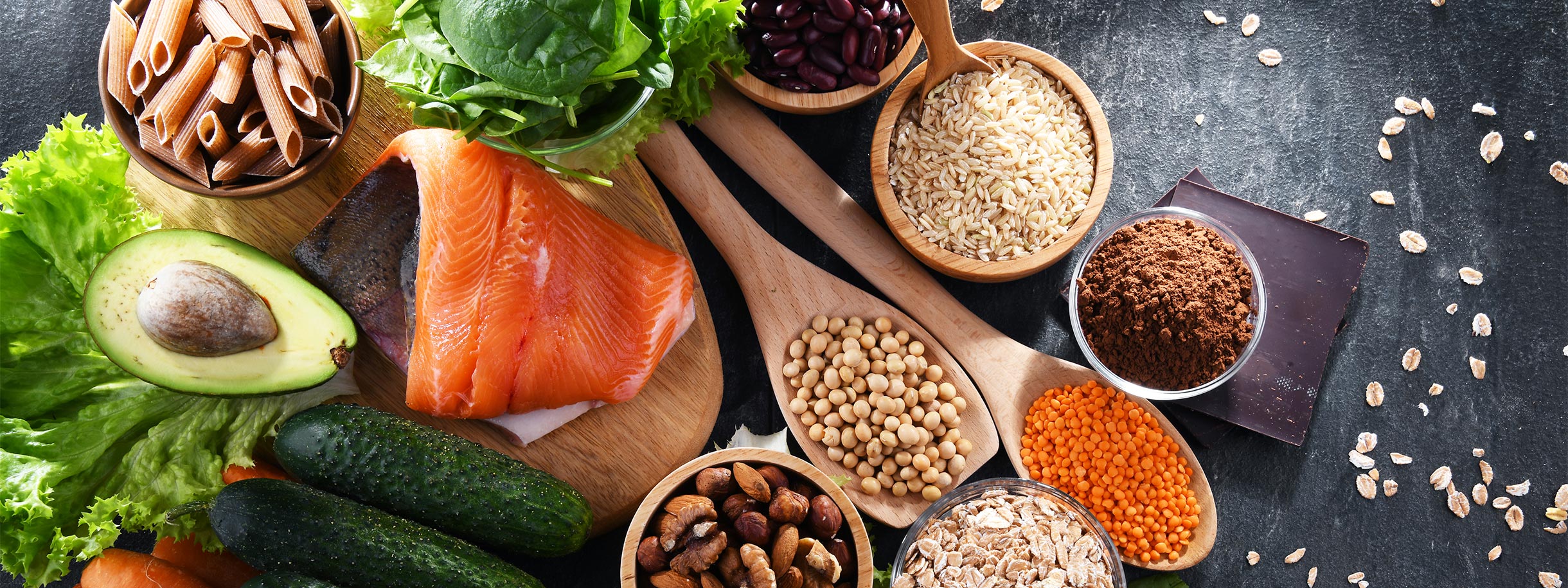 image of healthy foods including salmon, avocado, nuts, seeds, cucumbers, leafy greens and more