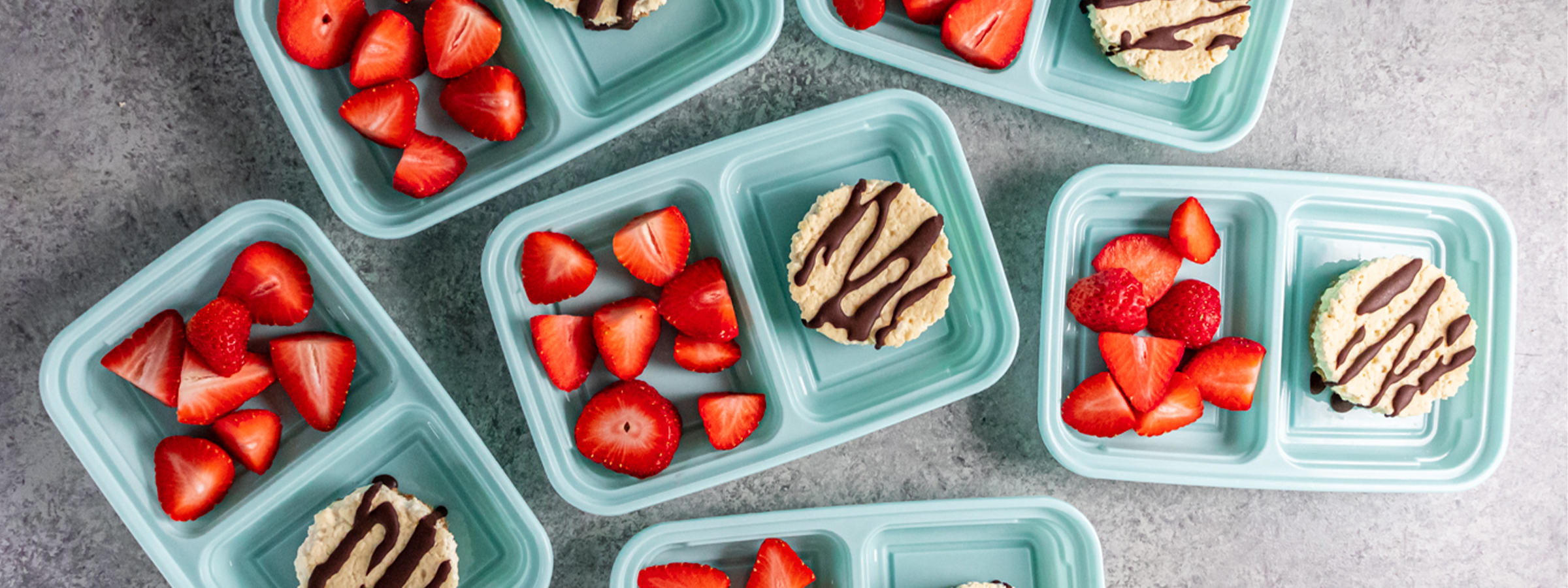 over head image of peanut butter cheesecake cups in blue containers along side strawberries