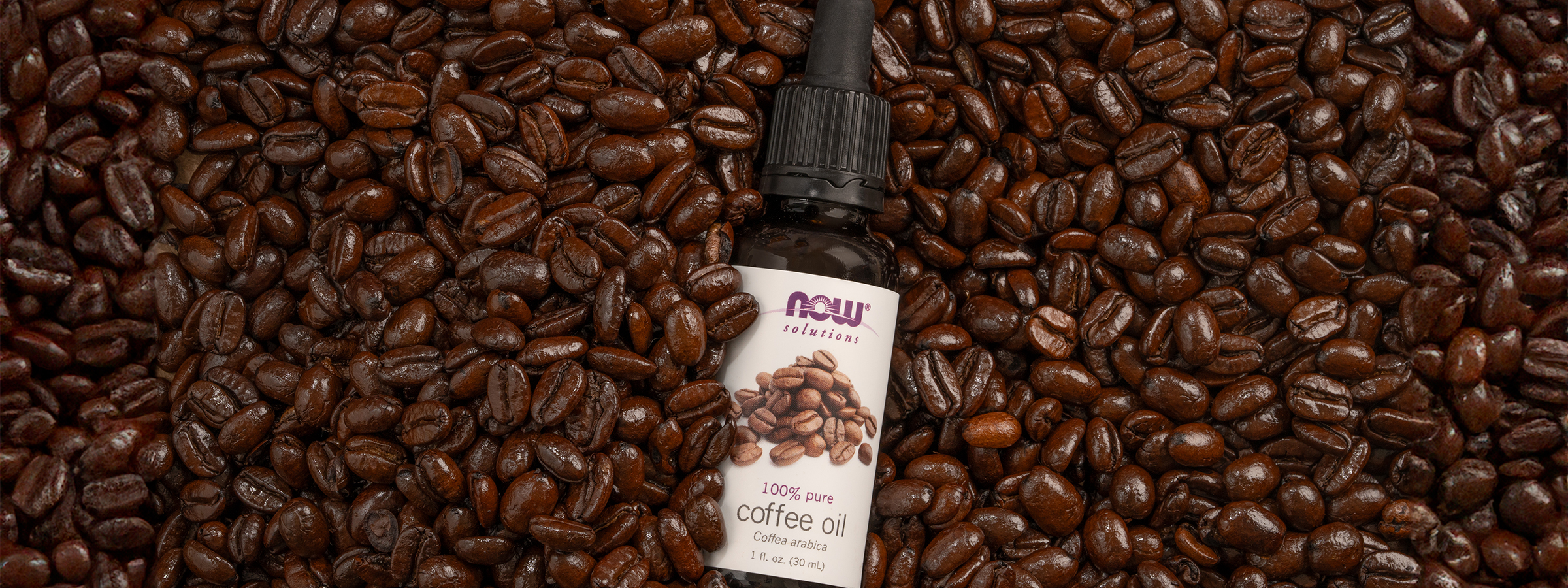 top view of NOW Coffee Oil on a bed of coffee beans