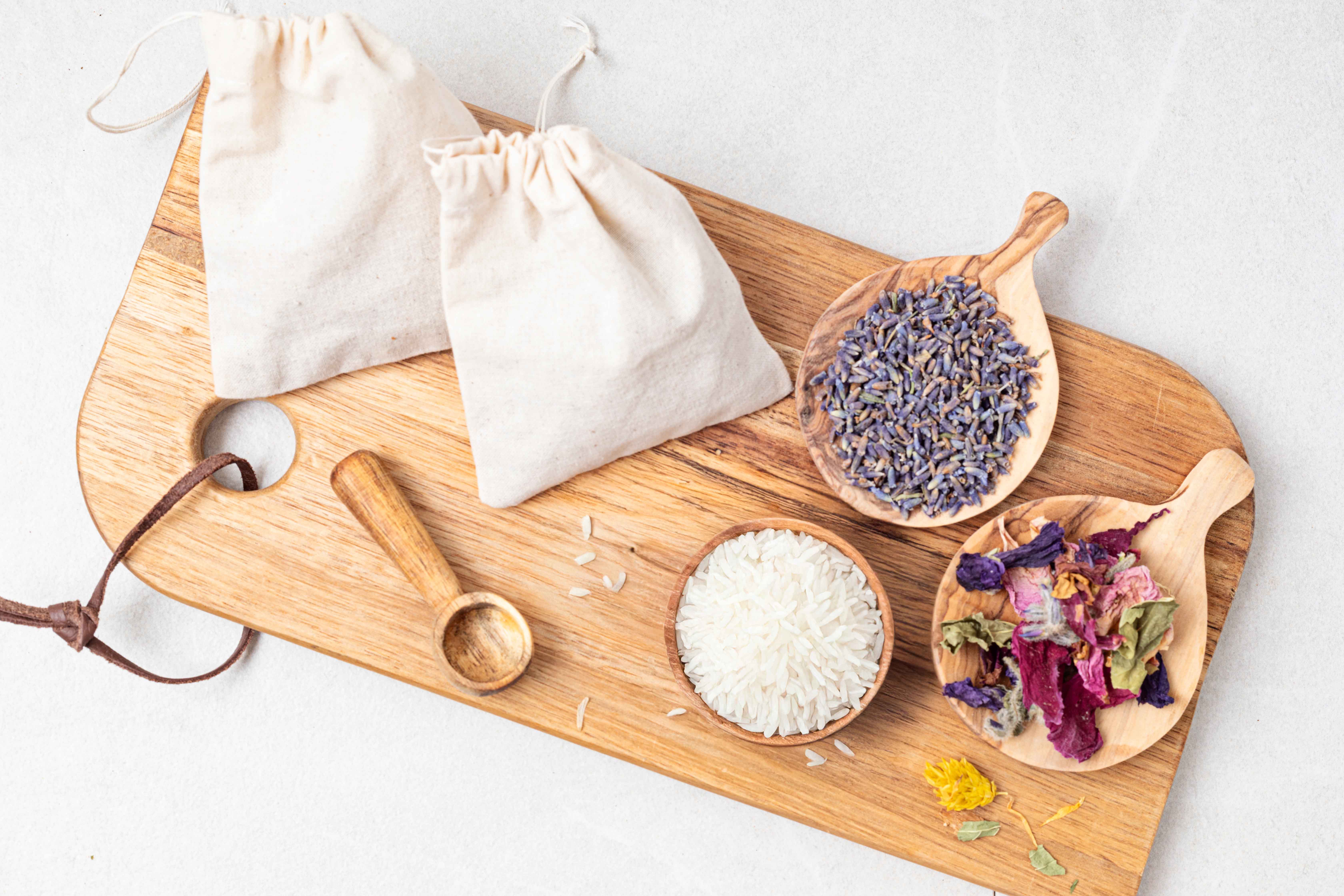 top view of Homemade Tea Tree and Lavender Essential Oil Sachets with lavender and rose petals on a wooden tray