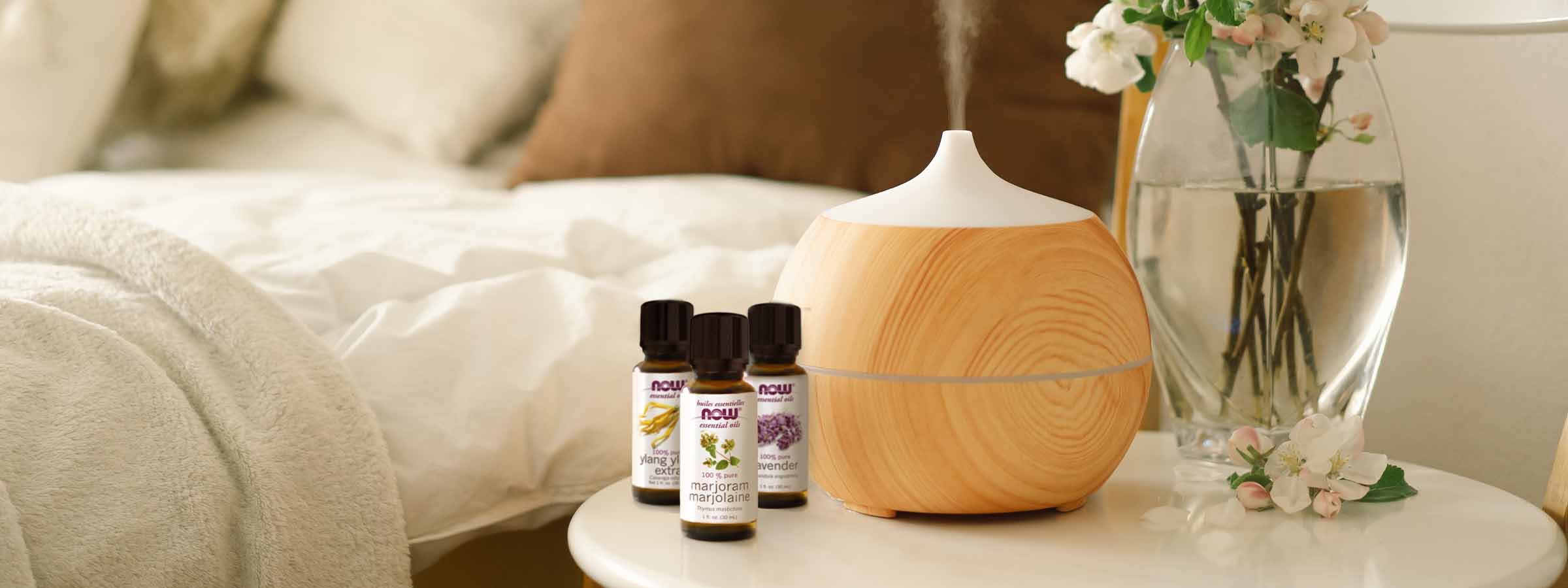 beige bedroom with a white table with a diffuser and NOW Essential oils