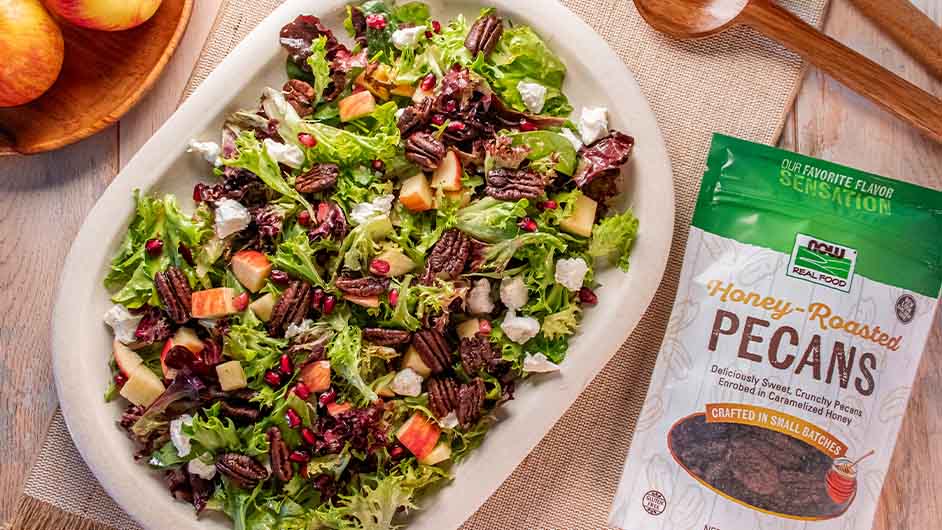 top view of a plate of Holiday Salad with Honey Roasted Pecans next to NOW Honey Roasted Pecans