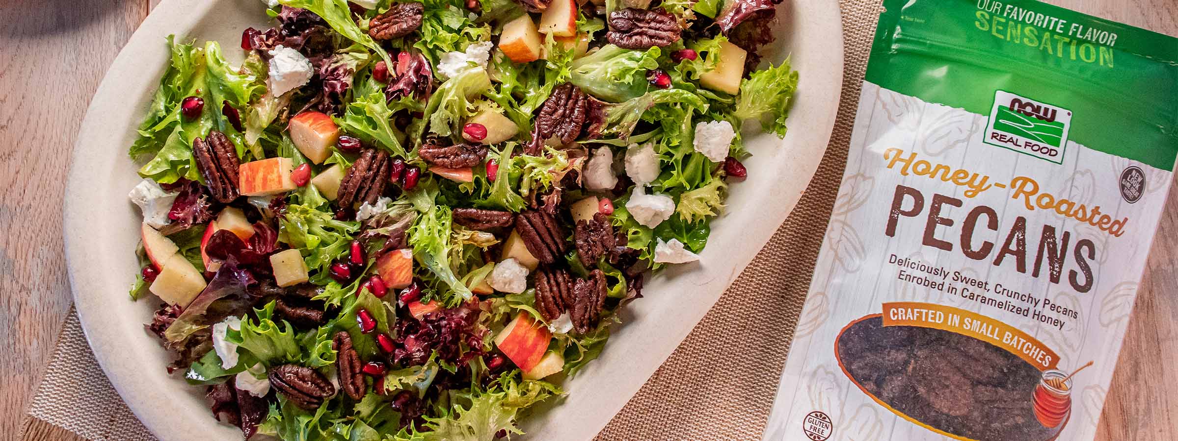 top view of a plate of Holiday Salad with Honey Roasted Pecans next to NOW Honey Roasted Pecans