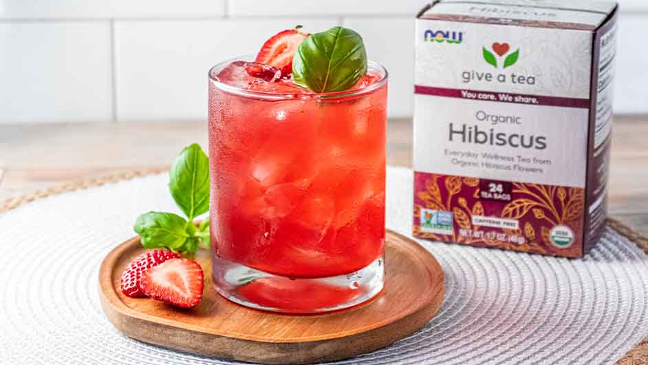 glass of Strawberry Hibiscus Aqua Fresca next to a box of NOW Hibiscus tea