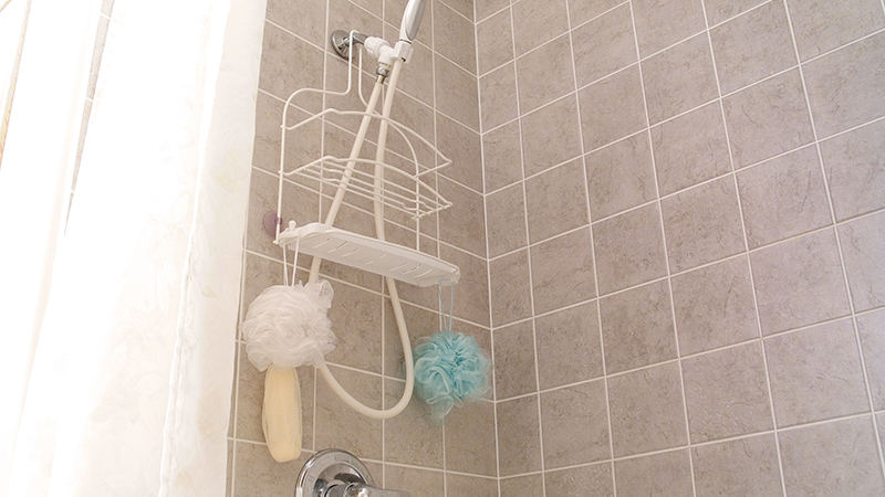 The inside of a shower with brown wall tile