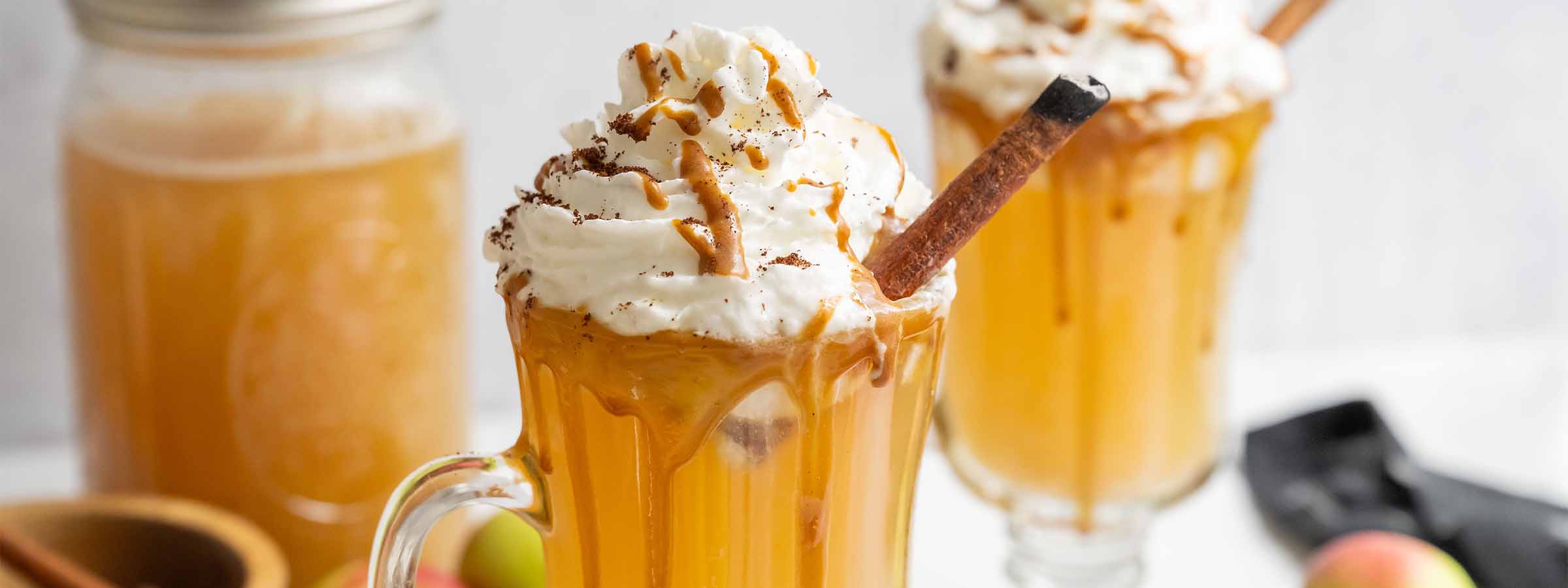 three glasses of Cozy Caramel Apple Cider with Whipped Cream and Cinnamon