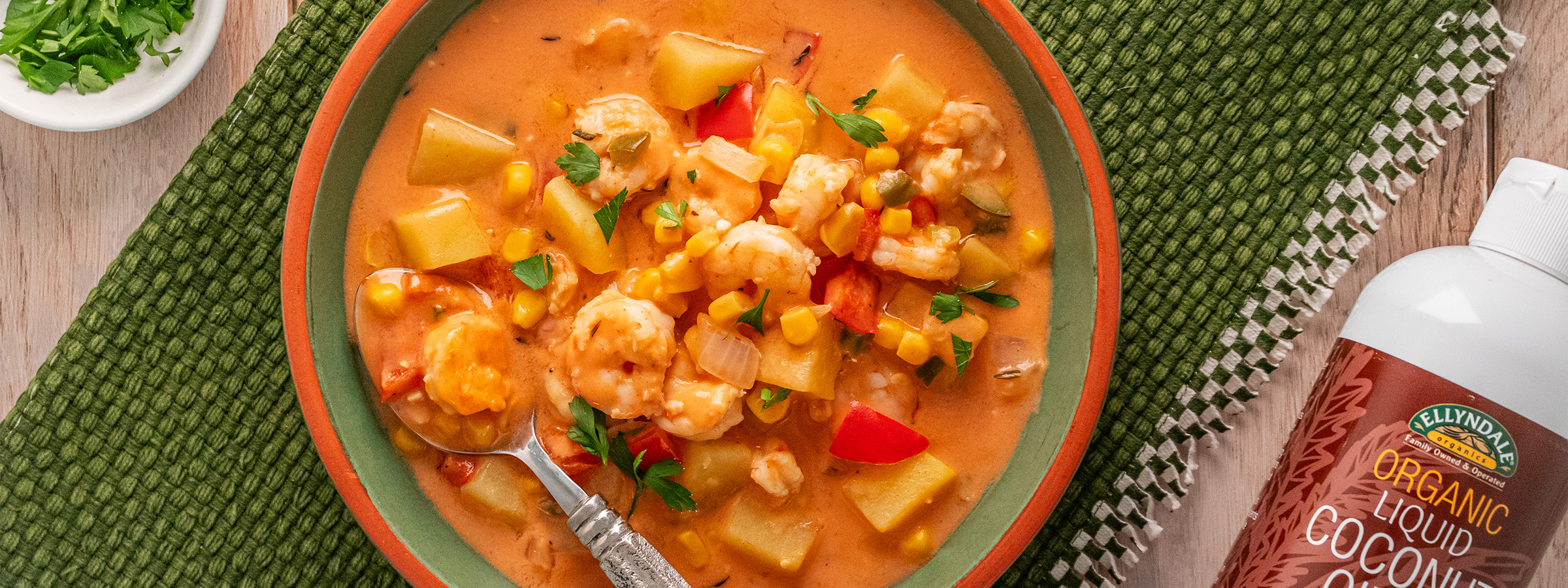 top view of Creamy Coconut Shrimp and Vegetable Chowder next to a bottle of Ellendales Coconut Cooking Oil
