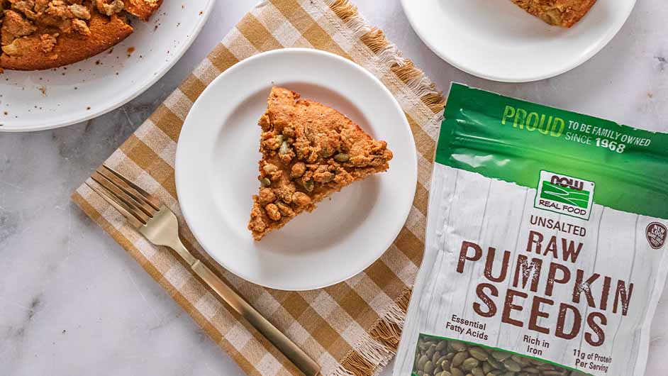 close up image of  Apple Spice Coffee Cake with Pumpkin Seed Crumble slice on white plate and checkered cloth