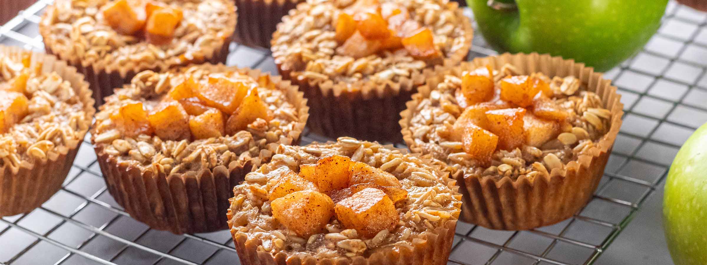 tray containing six Reduced Sugar Apple Oat Cups next to green apples