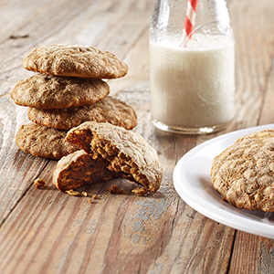 A rustic, wooden kitchen table with several flaky, light-brown Apple Oatmeal Breakfast Cookies