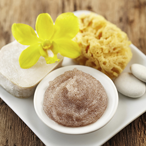 A small dish on a white platter holds Calming Sugar Body Scrub