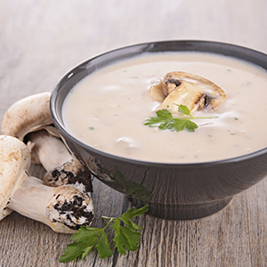 A dark grey soup bowl on a wooden table is full of Creamy Mushroom Soup. 