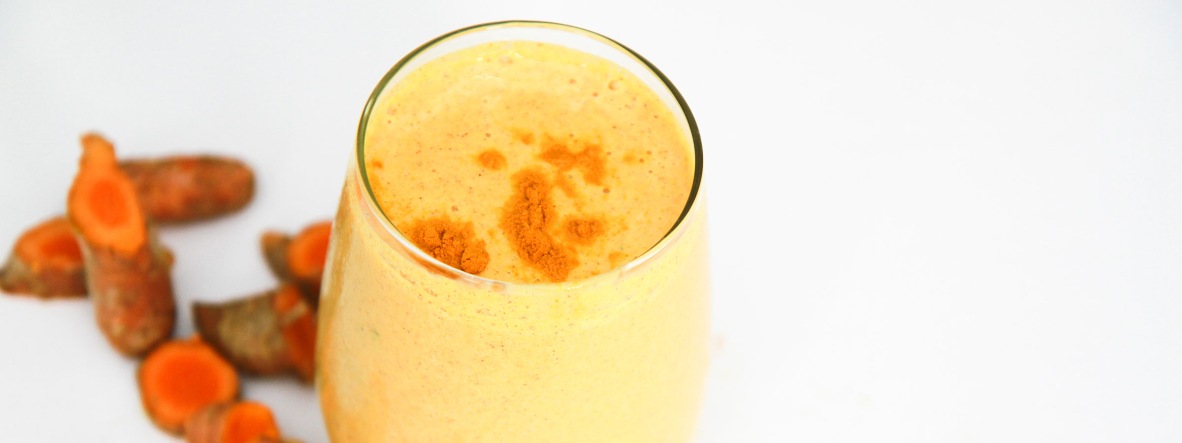 A tall, skinny drinking glass filled with a Creamy Vanilla Turmeric Smoothie.