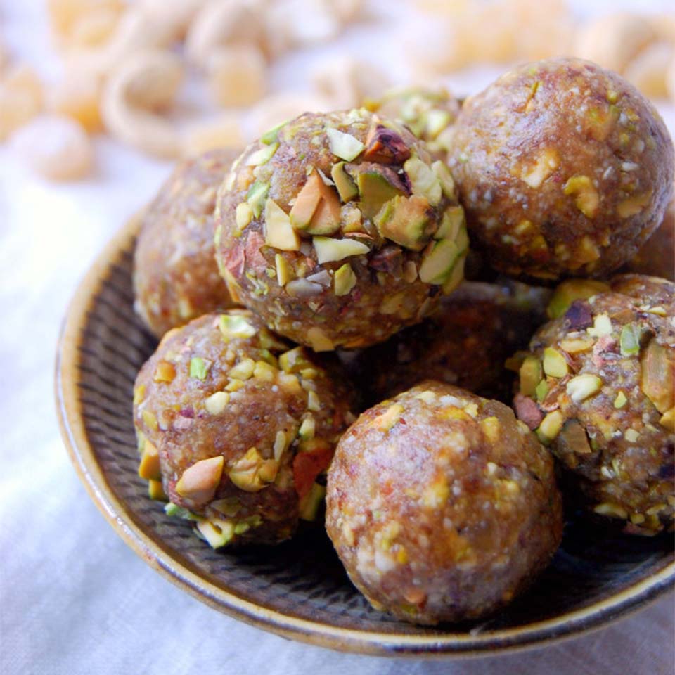 Ginger Pistachio Energy Bites are displayed on a plate as one inch sphere shapes of the completed recipe
