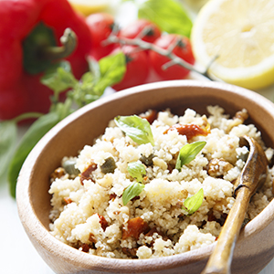 A small wooden bowl holding a dish of Mediterranean Couscous with Toasted Walnuts