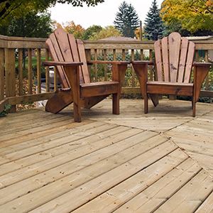 A suburban backyard wooden porch, prominently featuring two wooden deck chairs.