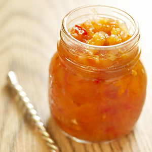 A mason jar on a wooden table holds several servings of Super Fruit Chutney.