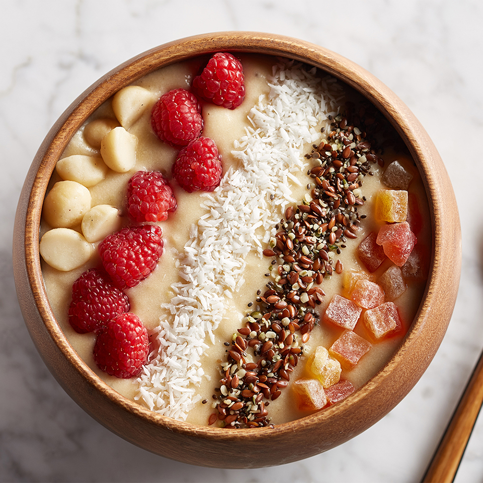 A wooden bowl on a white marble counter holds a serving of Tropical Omega Smoothie Bowl