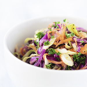 A closeup of a serving of Zesty Lime Slaw in a white ceramic bowl.