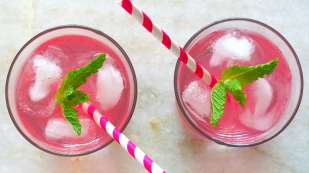 two pink drinks in a glass with ice, stripped straws and mint leaves