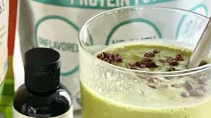 light green matcha chip smoothie in a glass surrounded by ingredients