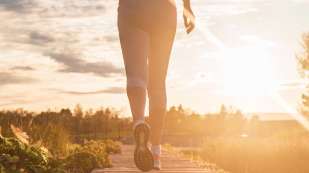 lower half of a person running into the sun on an outdoor path