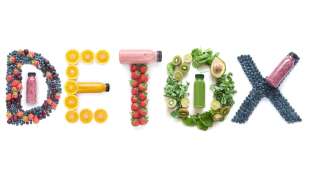 The word "detox" spelled out in fruits, vegetables, and bottles of smoothies