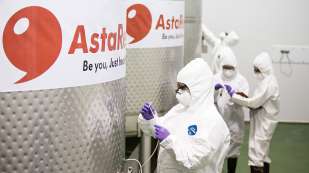 four people in white hazard suits working around Asta astaxanthin containers