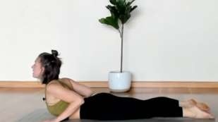 presenting as woman laying on stomach on a mat in black yoga pants with sports top with upper body raised up