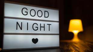 A sign with the inscription good night with turned on table lamp on the background