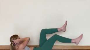 female presenting person wearing green pants doing a bicycle crunch