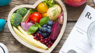 heart shaped container with vegetables and fruits surrounded by stethescope