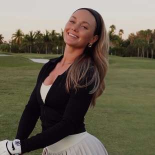 Sydney Grimes holding a golf club smiling at camera