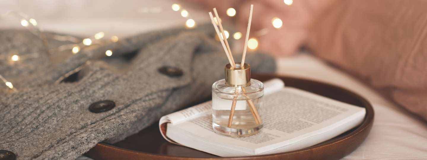 warm tones with christmas lights in the background and a gray sweater with a diffuser in the center on a book