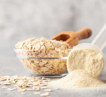 glass bowl with oatmeal next to a scoop of protein powder