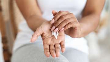 medium skinned female presenting person applying lotion to her hands