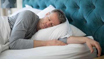 light skinned male presenting person sleeping in a bed