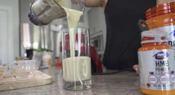 smoothie being poured into a glass NOW Sports HMB Powder next to glass
