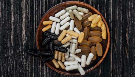 overhead view of dark wooden background with a bowl of supplements on top of it