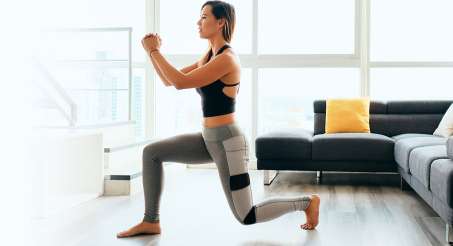 white female facing person doing a lunge in a bright living room