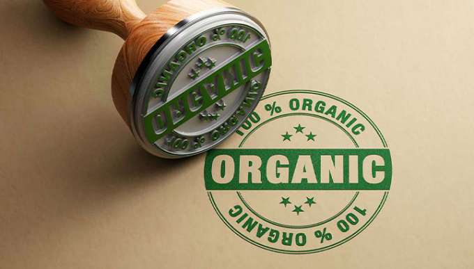 green stamp on tan background that says "100% Organic", the physical stamp is in the top left corner