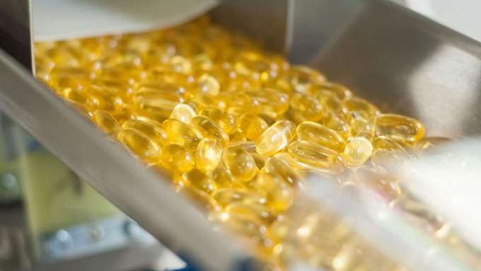 yellow softgel pills inside a metal manufacturing shoot