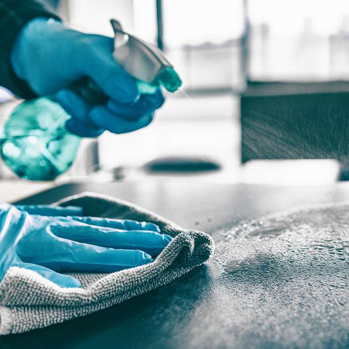 blue spray bottle, cleaning counter wearing blue rubber gloves