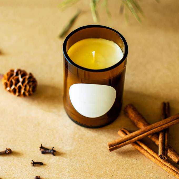 soy candle in a brown glass jar. cinnamon sticks on the table 