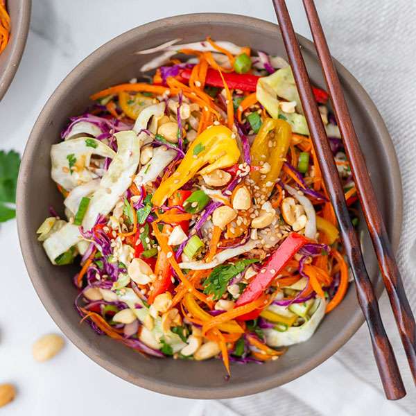 overhead view of brown bowl filled with very colorful Thai salad with chopsticks resting on the edge