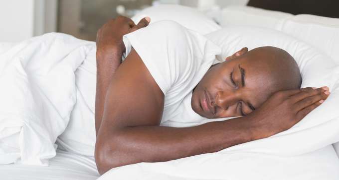 dark skinned male presenting person sleeping in bed 