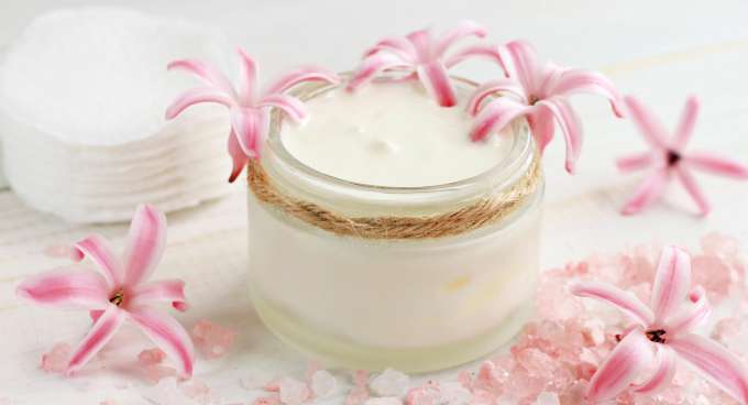 jar of peaceful sleep body butter surrounded by pink flowers